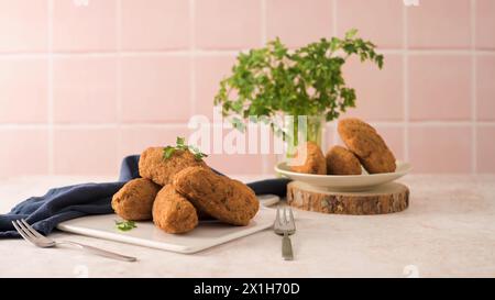 Kabeljauknödel oder „Bolinhos de bacalhau“ und Petersilienblätter auf weißen Keramikschüsseln in einer Küchenablage. Stockfoto
