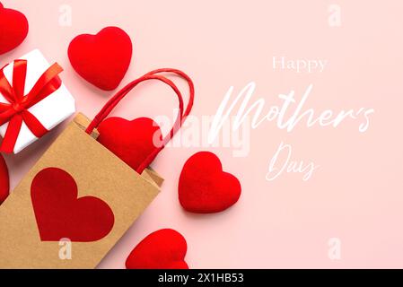 Alles Gute zum Muttertag. Blick von oben auf die Einkaufstasche mit einem roten Herzen, kleinen roten Herzen und der Text Happy Mothers Day auf rosa Hintergrund Stockfoto