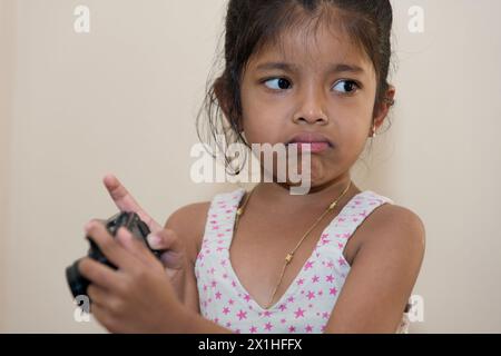 Ein junges Indianermädchen blickt aufgeregt durch einen Kamerasucher und ist bereit, einen besonderen Moment festzuhalten. Stockfoto