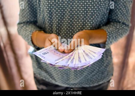 Ein Nahfoto von den Händen einer Frau, die akribisch Papiergeld zählt. Selektiver Fokus hebt die Rechnungen hervor Stockfoto