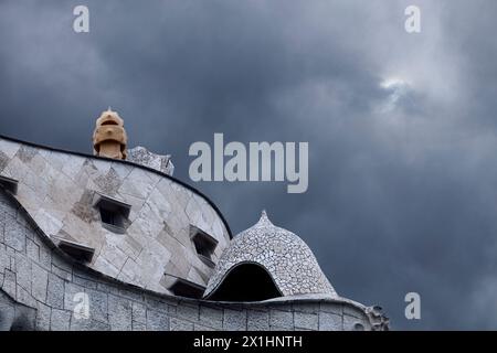 Ein Blick auf Casa Milà, bekannt als Pedrera, und seine berühmten Schornsteine, entworfen von Antoni Gaudí, über einem bewölkten Himmel. Barcelona - Spanien Stockfoto