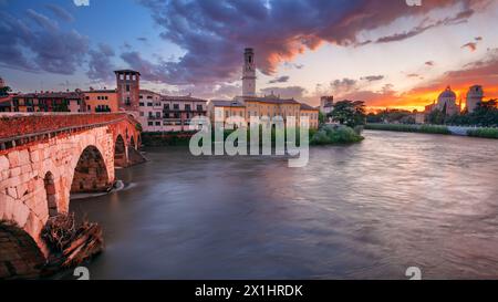 Verona, Italien. Stadtbild der wunderschönen italienischen Stadt Verona mit Steinbrücke über dem Fluss Adige bei Sonnenuntergang. Stockfoto
