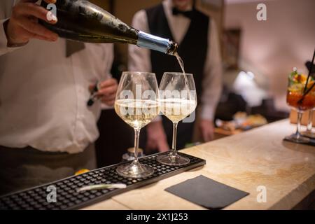 Der Barkeeper gießt Champagner in zwei Gläser Stockfoto