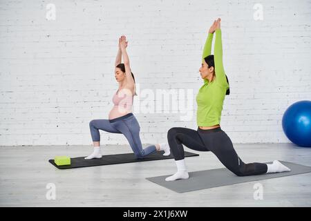 Eine schwangere Frau übt während eines Elternkurses auf einer farbenfrohen Matte anmutig Yoga mit ihrem Lehrer. Stockfoto