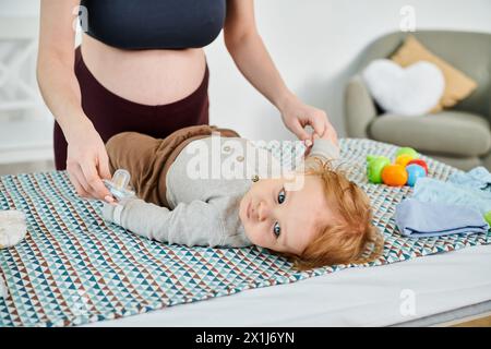 Ein Baby liegt friedlich neben einer jungen Frau auf einem Bett und fängt einen ruhigen und pflegenden Moment zwischen Mutter und Kind ein. Stockfoto