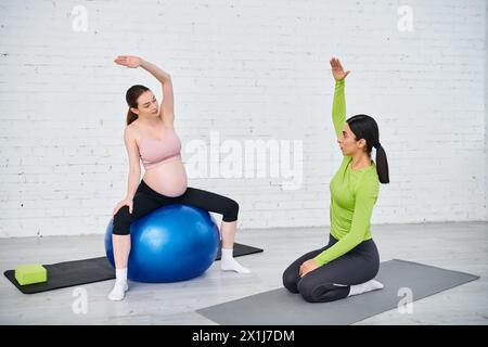 Schwangere Frau folgt ihrem Trainer und übt während der Elternkurse Yogapositionen auf den Bälle aus. Stockfoto