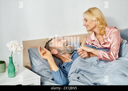 Ein Mann und eine Frau, ein reifes, liebevolles Paar, in gemütlicher Hauswäsche, liegen friedlich zusammen im Bett und teilen einen Moment der Intimität und Nähe. Stockfoto