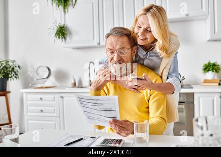 Ein reifes, liebevolles Paar in kuscheliger Hauswäsche, das ein mysteriöses Stück Papier in der Küche zu Hause untersucht. Stockfoto