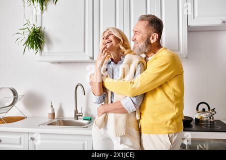 Ein reifes, liebevolles Paar in gemütlichen Haushaltswaren, das zusammen in der Küche steht und sich in Gesellschaft der anderen genießt. Stockfoto