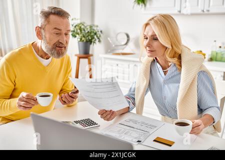 Ein reifer Mann und eine Frau in gemütlicher Kleidung sitzen an einem Tisch, arbeiten mit der Prüfung und Diskussion von Papierkram zusammen. Stockfoto