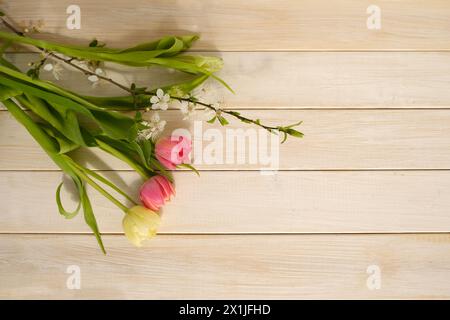 Leeres Modell in schöner Komposition auf Holztisch, Baumzweig mit Tulpenstrauß, Konzept Osterfreude, Frühlingserneuerung, natürlicher schöner Rücken Stockfoto