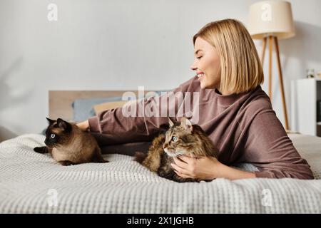 Eine ruhige Frau mit kurzen Haaren, die sich auf einem Bett mit zwei niedlichen Katzen an ihrer Seite entspannt. Stockfoto