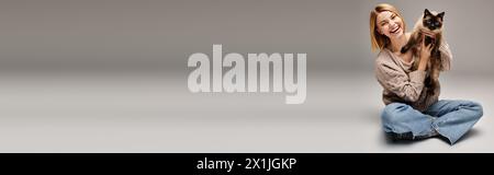 Eine Frau mit kurzen Haaren sitzt ruhig auf dem Boden und hält ihre geliebte Katze in einem herzerwärmenden Moment zu Hause. Stockfoto