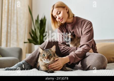 Eine Frau mit kurzen Haaren sitzt friedlich auf dem Boden und streichelt liebevoll ihre Katze. Stockfoto