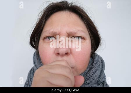 Close-up kranke reife Frau 55 Jahre Gesicht, kranke Person mit entzündeten Augen, die sich an Halsschmerzen festhält, hysterisch Husten, Konzept der Irritation, Stockfoto