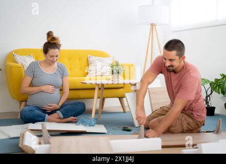 Schwangere Paare, die Möbel zusammenstellen und das Haus auf die Ankunft eines neuen Babys warten. Stockfoto