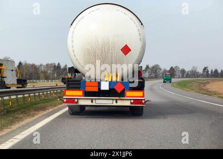 Ein Tankwagen mit Auflieger transportiert eine gefährliche Ladung von Benzin, Dieselkraftstoff und Erdölprodukten vor dem Hintergrund der Sonne auf die Straße. Stockfoto