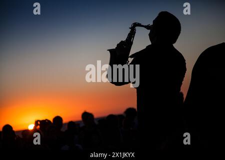 Junger Mann spielt Saxophon bei Sonnenuntergang vor der Öffentlichkeit in Südspanien Stockfoto