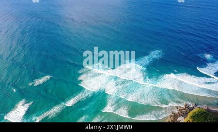 Gemusterte, schaumige Meereswellen Rollen herein und nähern sich dem Sandstrand. Majestät türkisfarbenes Meer. Draufsicht der Drohne Stockfoto
