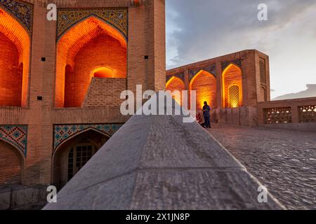 Blick auf die beleuchteten Gewölbebögen der Khaju-Brücke aus dem 17. Jahrhundert auf dem Fluss Zayanderud in der Abenddämmerung. Isfahan, Iran. Stockfoto