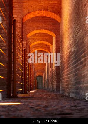 Ein flacher Blick durch beleuchtete gewölbte Bögen der Khaju-Brücke aus dem 17. Jahrhundert auf dem Fluss Zayanderud in Isfahan, Iran. Stockfoto