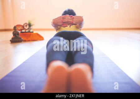 Die nicht erkennbare Frau Yogi hält die Hände hinter dem Rücken und liegt mit dem Gesicht nach unten Stockfoto