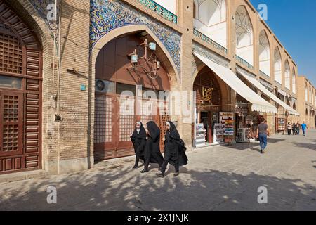 Iranische Frauen in schwarzen Chadors gehen gemeinsam auf dem Naqsh-e Jahan-Platz, dem UNESCO-Weltkulturerbe. Isfahan, Iran. Stockfoto