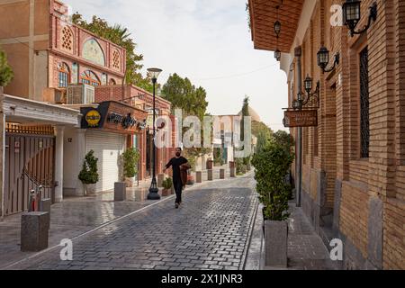 Ein Mann läuft in einer engen Kopfsteinpflasterstraße in New Julfa, armenischer Nachbarschaft von Isfahan, Iran. Stockfoto