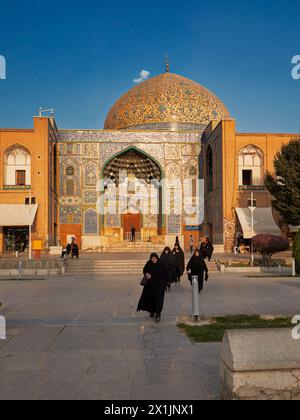 Iranische Frauen mit schwarzen Chadors gehen an der Lotfollah-Moschee auf dem Naqsh-e Jahan-Platz. Isfahan, Iran. Stockfoto