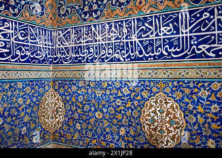 Nahaufnahme hochaufwendiger Fliesenarbeiten mit Arabesken-Mustern und koranischer Kalligraphie an Wänden in der Shah-Moschee (Masjed-e Shah). Isfahan, Iran. Stockfoto