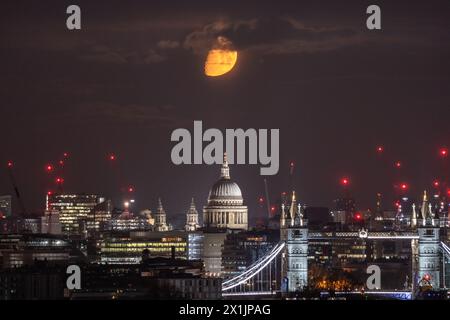 London, Großbritannien. April 2024. Wetter in Großbritannien: Moonset sieht einen hellen, zu 59 % wachsenden Gibbous Mond, der in den frühen Morgenstunden des Mittwochs über die Stadtlandschaft absteigt und sich mit St. St. NW in WNW-Richtung bewegt Paul's Cathedral und Tower Bridge Sehenswürdigkeiten im Blick. Guy Corbishley/Alamy Live News Stockfoto