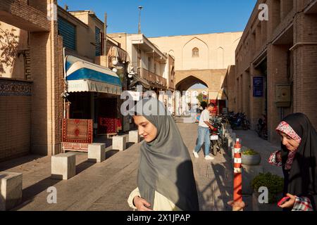 Junge iranische Frauen in Hijabs laufen in einer engen Straße im historischen Zentrum von Isfahan, Iran. Stockfoto