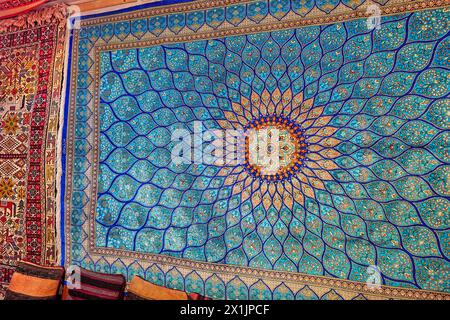 Großer persischer Seidenteppich mit kompliziertem blauen Muster, der an einer Wand in einem Teppichgeschäft ausgestellt ist. Isfahan, Iran. Stockfoto