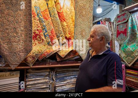 Porträt eines Verkäufers in einem Kunsthandwerksladen, der Termeh verkauft, ein traditionelles persisches handgewebtes Tuch, bestickt mit Seide. Isfahan, Iran. Stockfoto