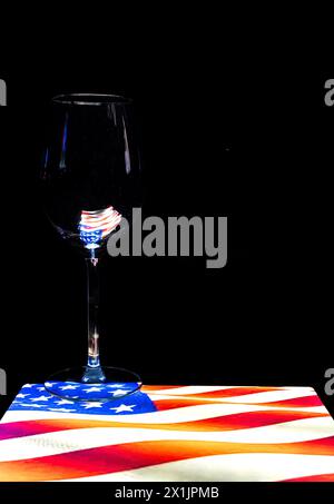 Ein leeres Weinglas auf der amerikanischen „Stars & Stripes“-Flagge. Stockfoto