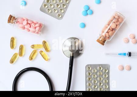 Stethoskop auf weißem Hintergrund, Draufsicht. Medizinisches Instrument und verschiedene Medikamente, Tabletten, Kapseln und Spritzen. Medizin und Gesundheitswesen Stockfoto