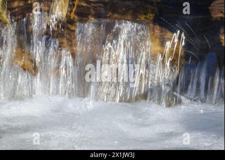 Eine ruhige Wasserkaskade fließt über natürliche Felsen und erzeugt einen verschwommenen, seidigen Effekt. Stockfoto