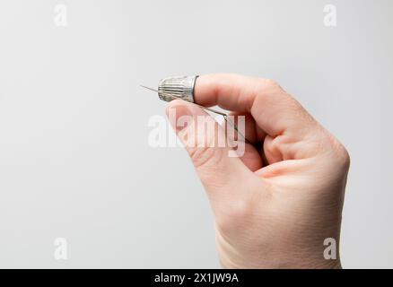 Frau, die zu Hause einen Fingerhut oder Fingerschild verwendet. Leerzeichen auf weißem Hintergrund kopieren. Stockfoto