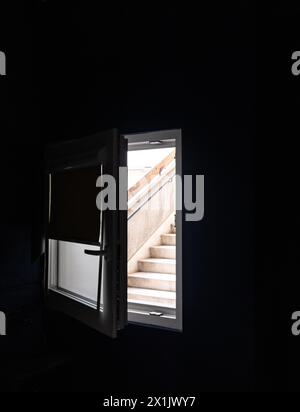 Betontreppe durch ein Schlafzimmer-Fenster in einem düsteren Wohnblock. Stockfoto