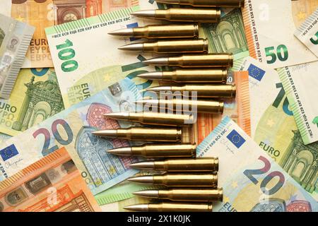 Gelbe Kartuschen und Schalen auf Euro-Banknoten. Viele Geldscheine der Europäischen union und Munition aus der Nähe Stockfoto