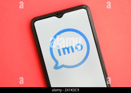KIEW, UKRAINE - 1. APRIL 2024 IMO Messenger-Symbol auf dem Smartphone-Bildschirm auf dem roten Tisch Nahaufnahme. IPhone-Display mit App-Logo auf hellrotem Hintergrund Stockfoto