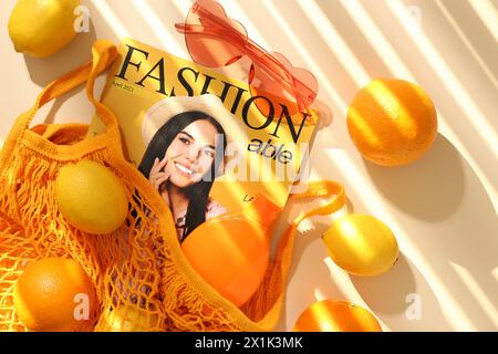 Schnur Tasche mit frischem Obst, Modemagazin und Strandaccessoires auf beigefarbenem Hintergrund, flache Lay Stockfoto