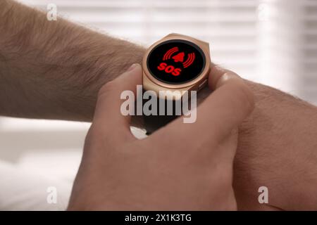 Mann mit SOS-Funktion bei Smartwatch drinnen, Nahaufnahme Stockfoto