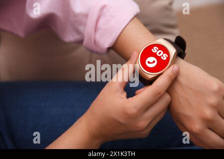 Frau mit SOS-Funktion bei Smartwatch drinnen, Nahaufnahme Stockfoto