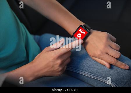 Frau mit SOS-Funktion auf Smartwatch im Auto, Nahaufnahme Stockfoto