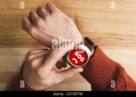 Mann mit SOS-Funktion auf Smartwatch am Holztisch, Nahaufnahme Stockfoto