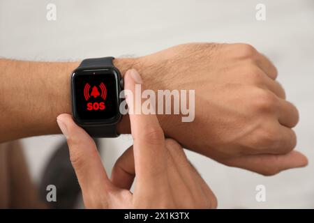 Mann mit SOS-Funktion bei Smartwatch drinnen, Nahaufnahme Stockfoto