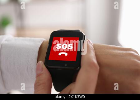 Frau mit SOS-Funktion bei Smartwatch drinnen, Nahaufnahme Stockfoto