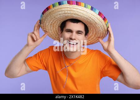Junger Mann mit mexikanischem Sombrero-Hut auf violettem Hintergrund Stockfoto
