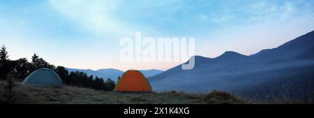 Campingzelte am Berghang am Morgen, Bannerdesign Stockfoto